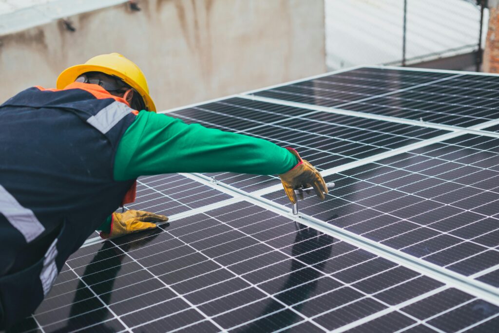 pexels-photo-8853502-8853502 Technician installing solar panels on a rooftop for sustainable energy solutions.